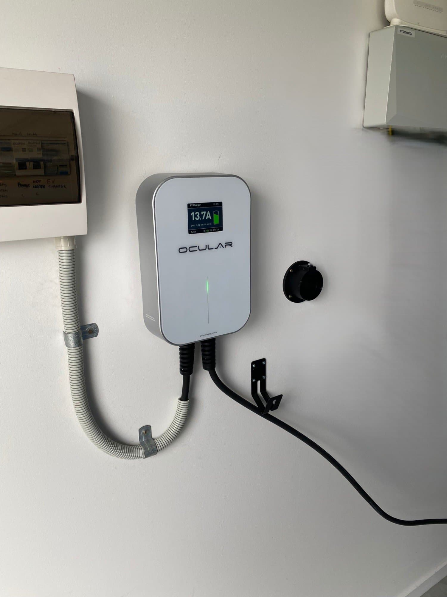 Ocular EV charger installed next to the switchboard, mid-charge at 13.7A